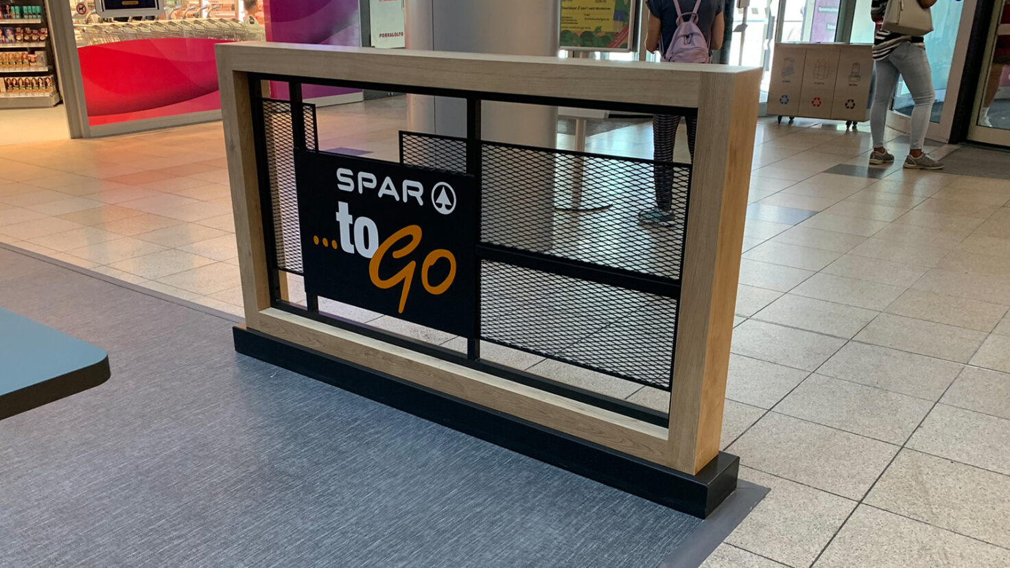 unbeleuchtets Schild mit Spar to go Logo auf einem Raumteiler