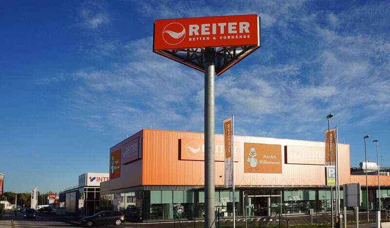 Werbeturm bestehend aus einem Betonmast mit drei Leuchtschildern von HUBER Signage
